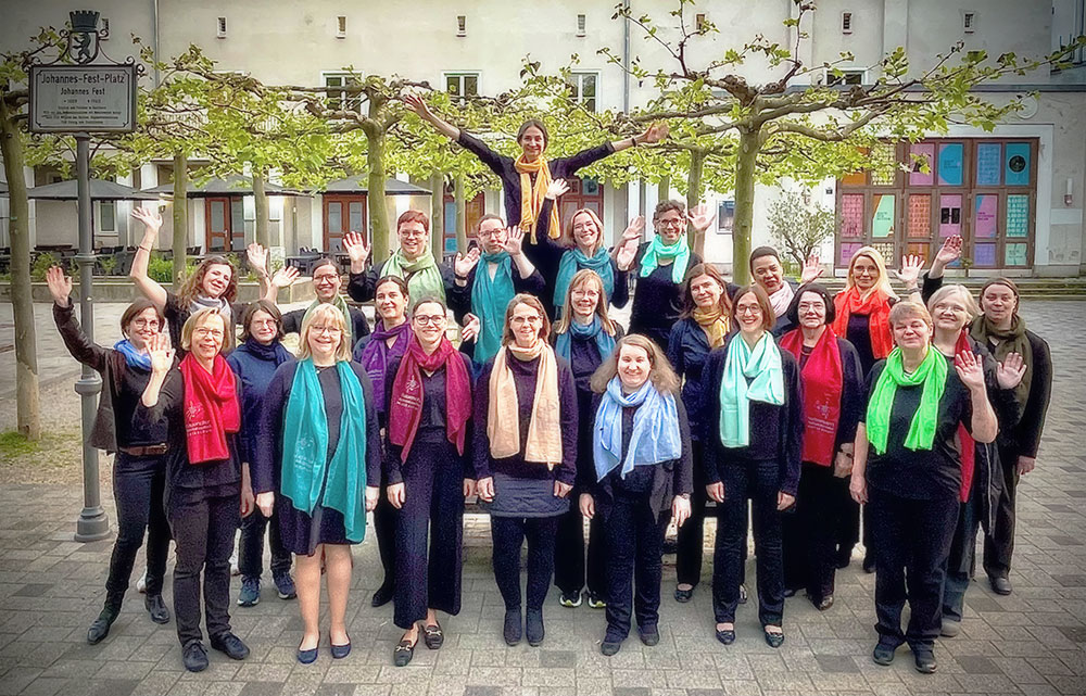24 Chorsängerinnen stehen fröhlich auf dem Stadtplatz hinter unserem Standort Karlshorst